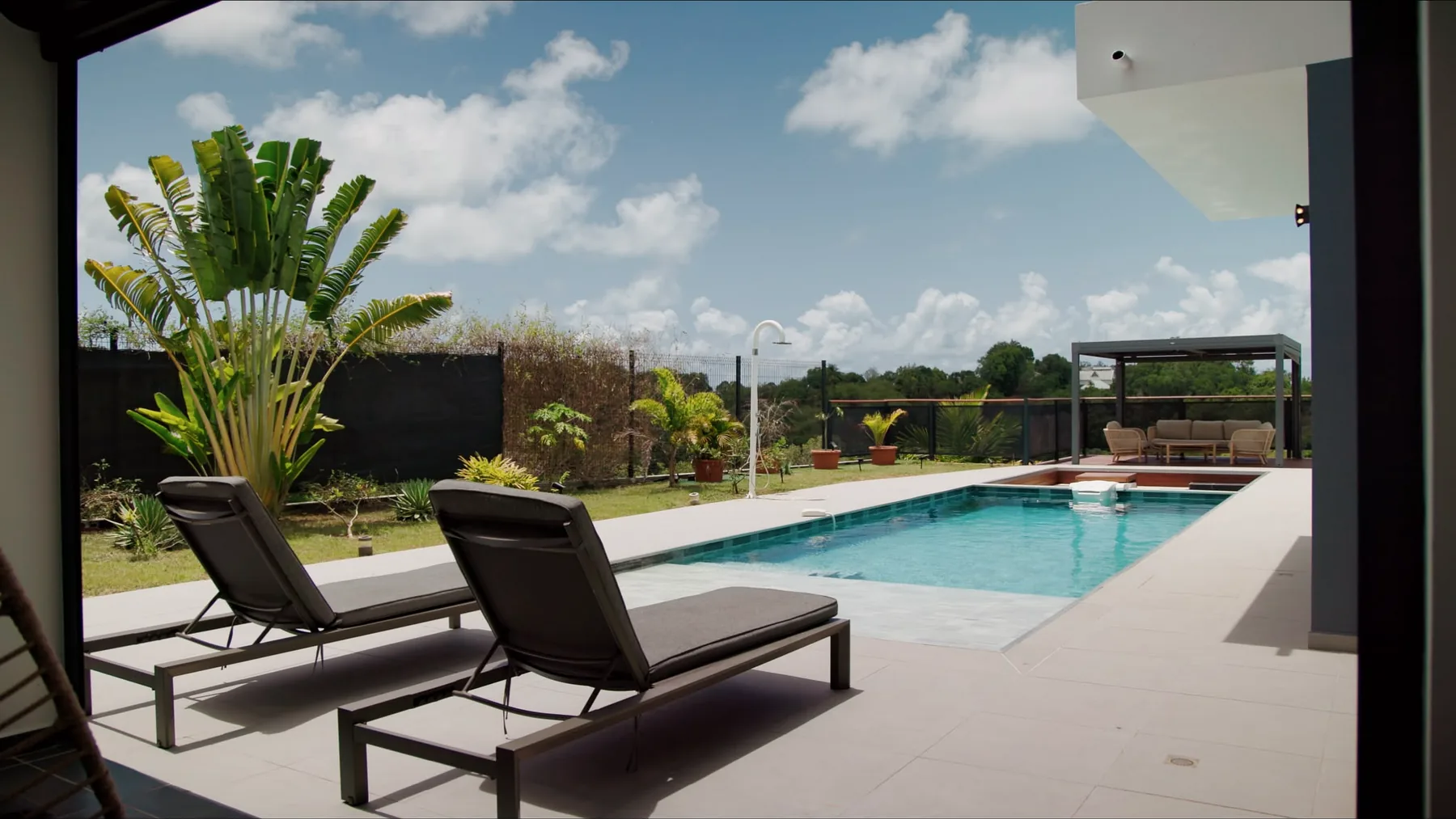Transats au bord de la piscine de la Villa Rapha, jardin tropical et ciel des Antilles